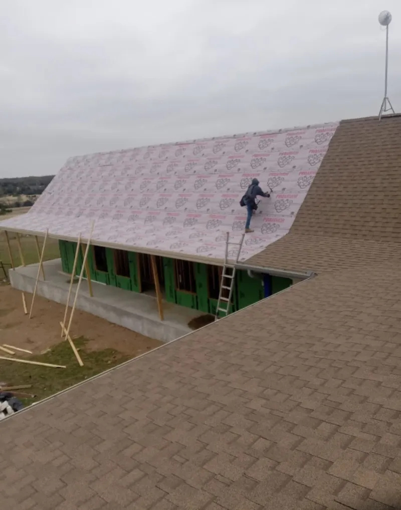 Worker preparing underlayment for a metal roof installation in Lafayette